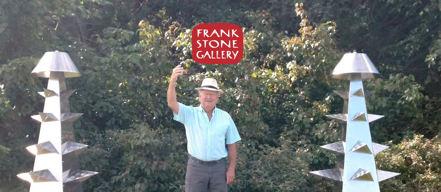 Frank Stone standing between sculptural outdoor pieces